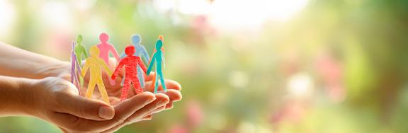 A pair of hands supporting a ring of paper cut-out human figures