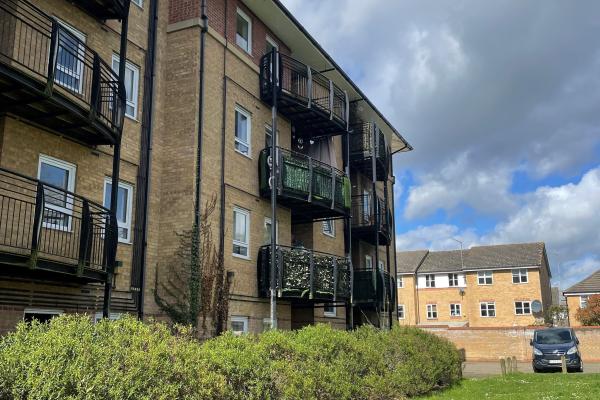 A modern 4-storey block of flats with balconies and garden surrounds